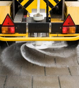 A machine is sprinkling salt on a sidewalk